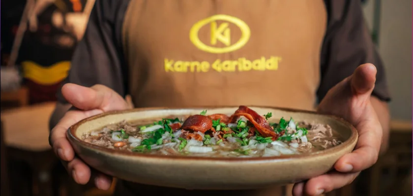 Plato de carne en su jugo presentado con ambas manos